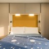 Letto matrimoniale con copriletto blu a tema spaziale, parete gialla e armadi grigi.